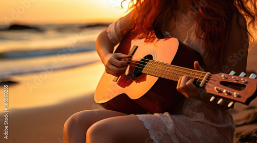 Beautiful romantic curly woman, with a guitar, sitting on the beach at sunset. Space for text