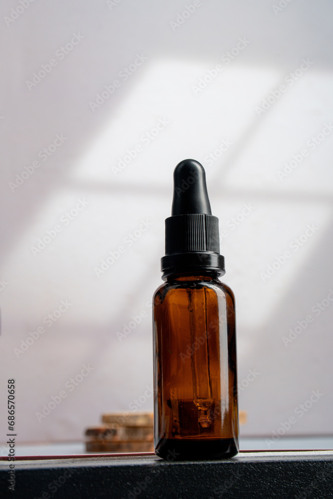 Cosmetic bottles made of dark amber glass on white background with window leaves shadow.