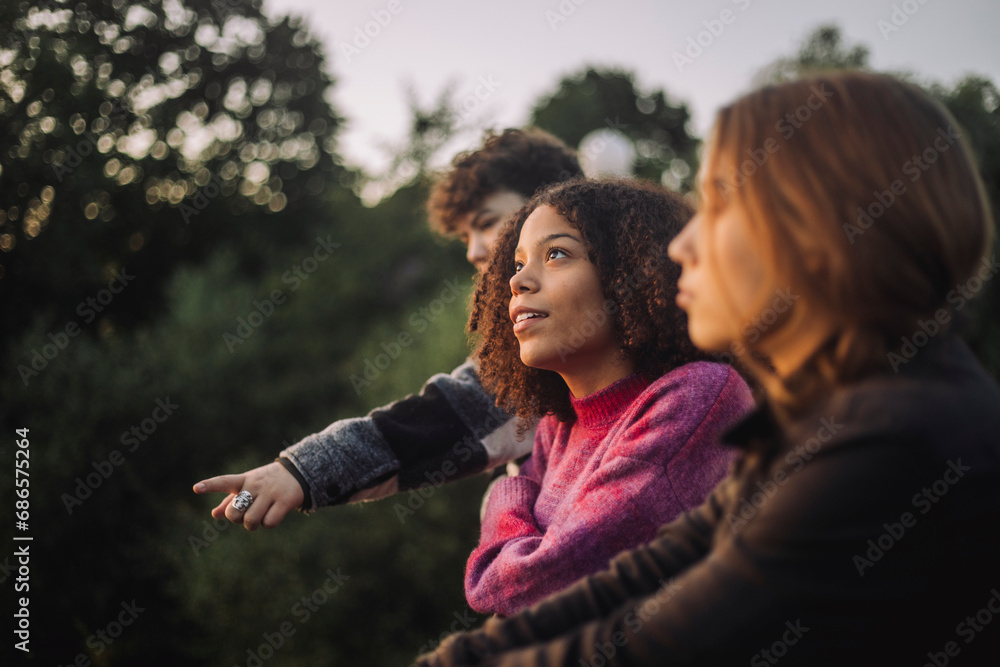 Thoughtful girl day dreaming with friends at sunset Thoughtful girl day dreaming with friends at sunset