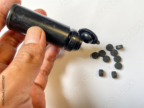 Male hand with activated carbon pills  near table