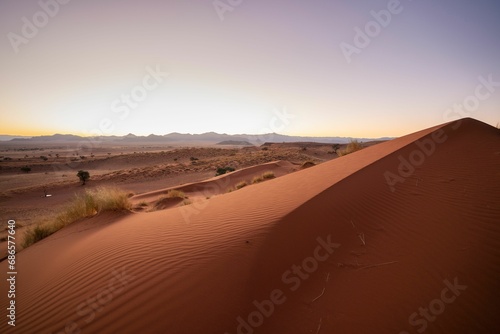 Serene landscape of dunes silhouetted against the backdrop of a setting sun