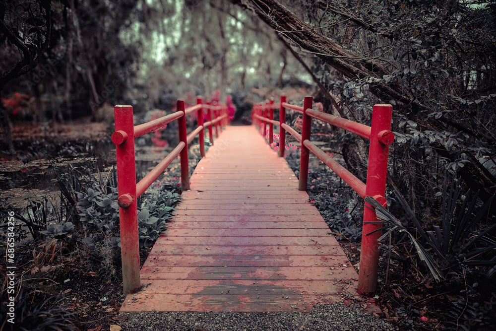 Red bridge ina romantic garden with oak trees and spanish moss