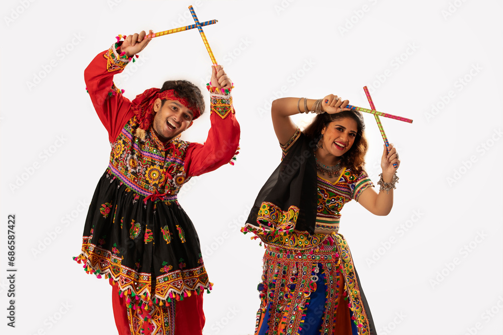 Portrait of happy young couple performing Dandiya Raas during Navratri ...