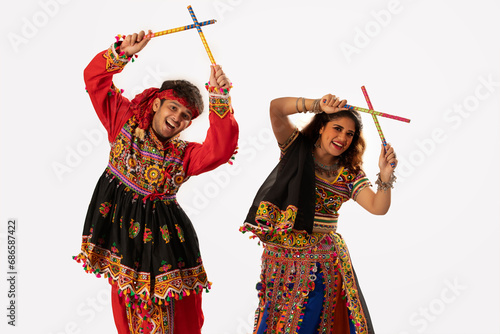 Portrait of happy young couple performing Dandiya Raas during Navratri celebration