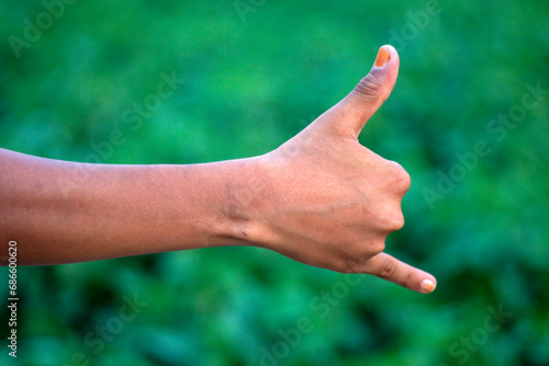 A man is pointing one finger of his hand forward and the thumb is pointing up and green background © Rokonuzzamnan