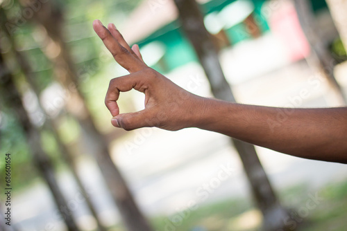A man points three fingers upwards and two fingers together circle and blur background