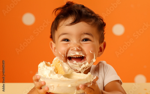 A happy child devours a cake and smears cream on his face