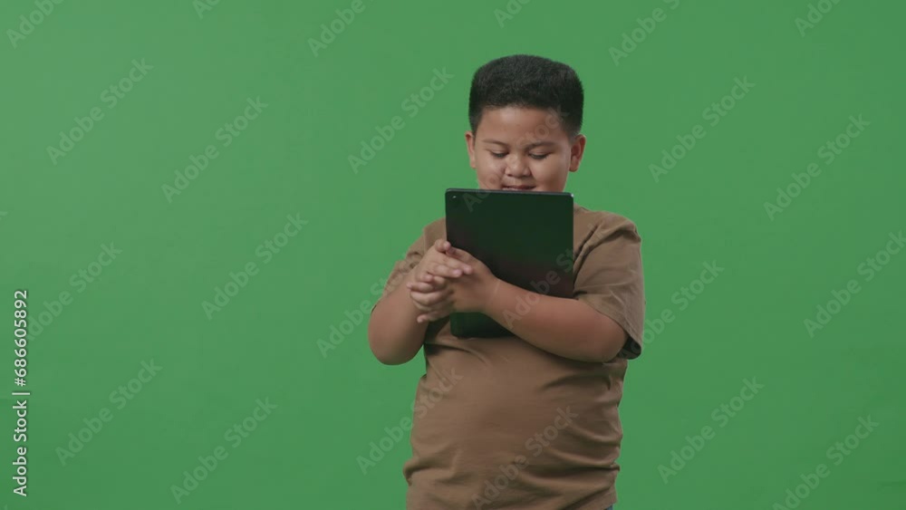 An Asian Boy Smiling While Using Tablet On Green Screen Background In The Studio
An Asian Boy Smiling While Using Tablet On Green Screen Background In The Studio