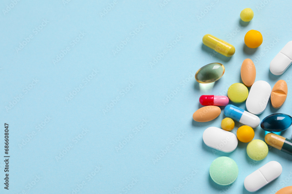 Many different pills on light blue background, flat lay. Space for text
