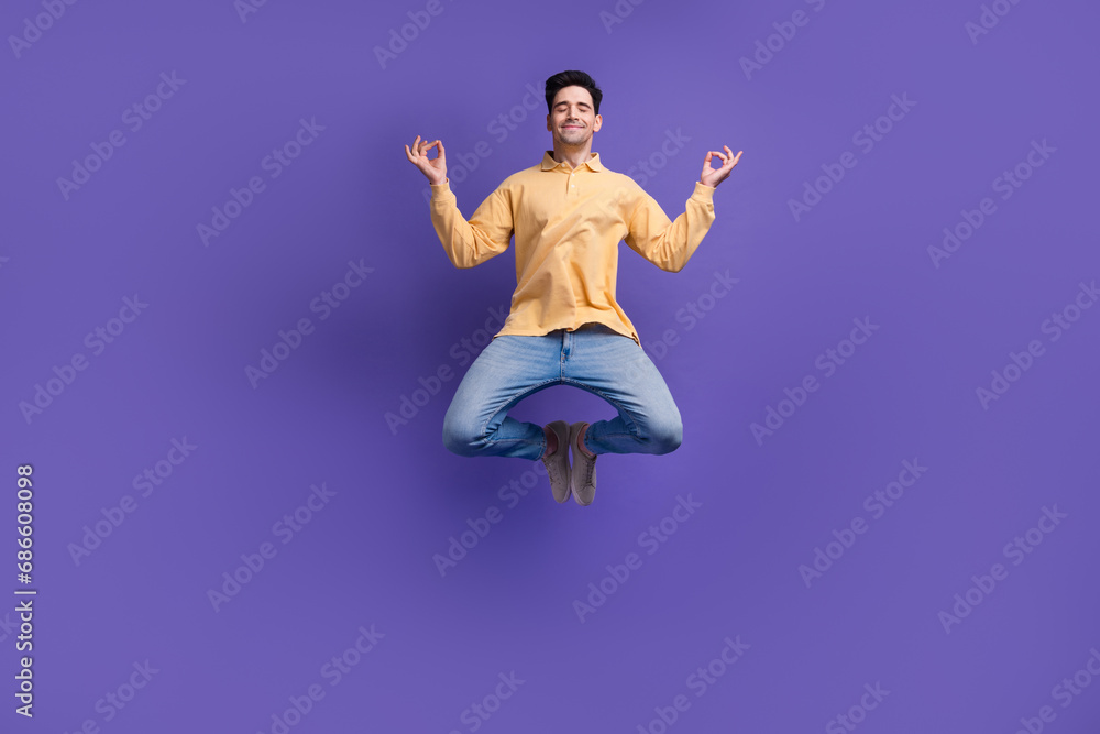 Full body photo of nice young male jump meditate levitate closed eyes wear trendy yellow outfit isolated on violet color background
