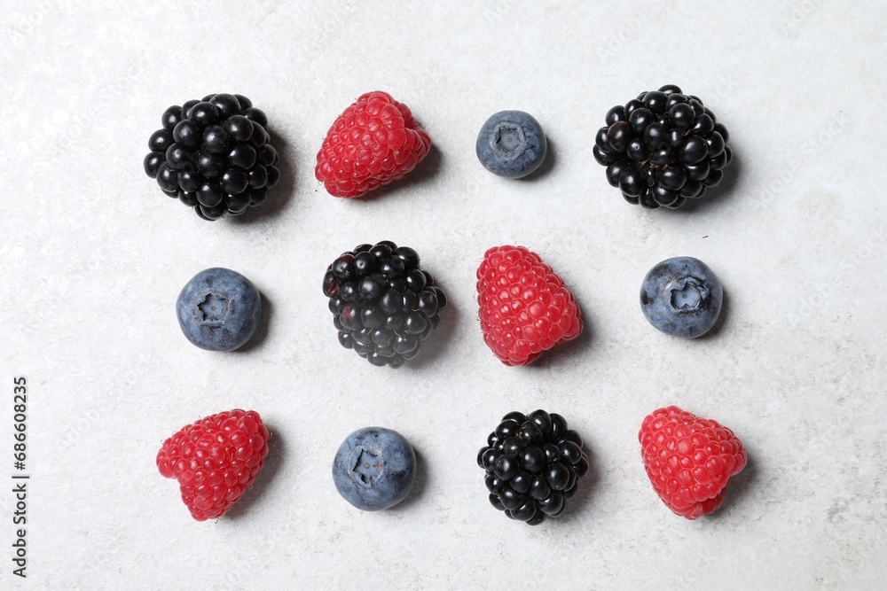 Many different fresh ripe berries on white textured table, flat lay Many different fresh ripe berries on white textured table, flat lay