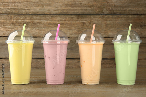 Plastic cups with different tasty smoothies on wooden table