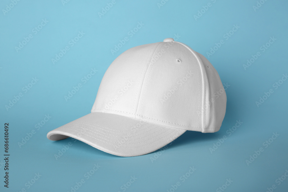 Stylish white baseball cap on light blue background Stylish white baseball cap on light blue background