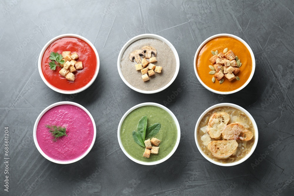 Different tasty cream soups in bowls on dark grey table, flat lay Different tasty cream soups in bowls on dark grey table, flat lay