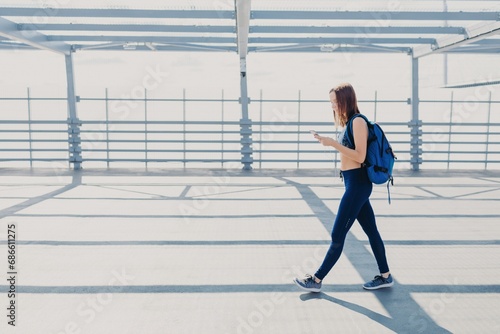 Active woman walking with phone and backpack in urban scene