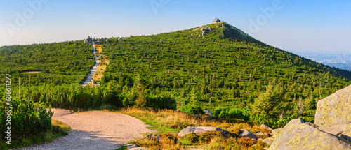 Karkonosze Mountains, Western Sudetes, mountain hiking trail leading along the plain through the peaks, natural mountain landscape with high-mountain vegetation on a sunny summer day.