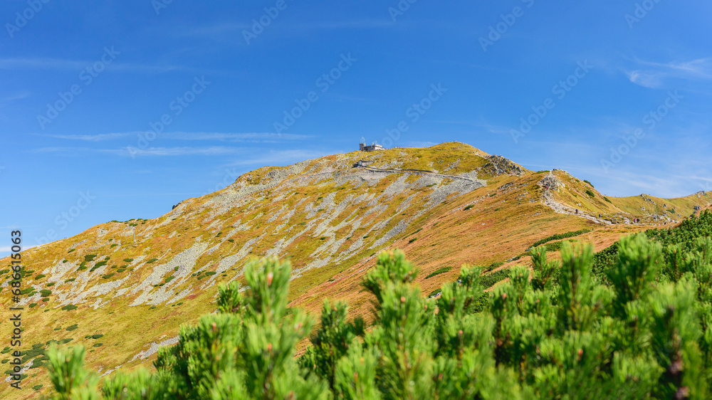 Polish Tatra Mountains, high mountain hiking trail leading to mountain peaks, mountain landscape with valleys and slopes, view on a sunny summer day.View of the Kasprowy Wierch mountain peak. Polish Tatra Mountains, high mountain hiking trail leading to mountain peaks, mountain landscape with valleys and slopes, view on a sunny summer day.View of the Kasprowy Wierch mountain peak.