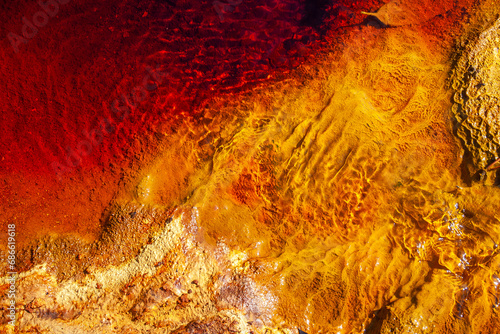 Detail of the rocky bottom and water ripples of the Rio Tinto (Spain). The red colour of the river is due to the dissolution of minerals (oxides and iron) that occurs because its water is very acidic