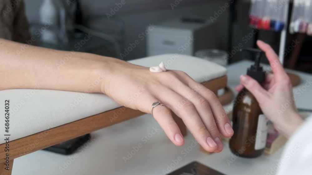 Closeup on woman manicurist doing massage for client hands and applying cream after manicure procedure at beauty salon. Nail care and self care concept Closeup on woman manicurist doing massage for client hands and applying cream after manicure procedure at beauty salon. Nail care and self care concept