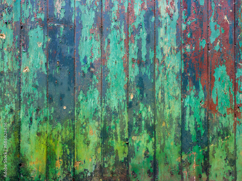 green and red peeling paint on old wooden planks of shed
