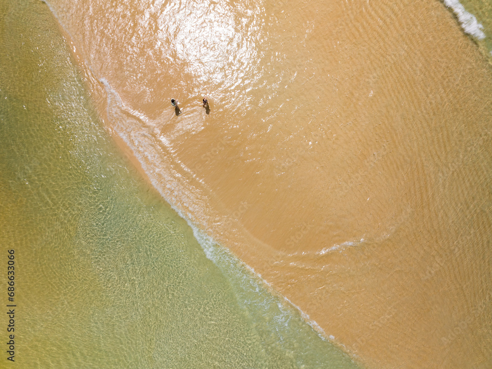 Fototapeta premium Aerial view of Waves crashing on sandy shore,Sea surface ocean waves background,Top view beach background