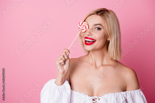 Photo of shiny sweet girl dressed off shoulders outfit lollipop cover eye empty space isolated pink color background