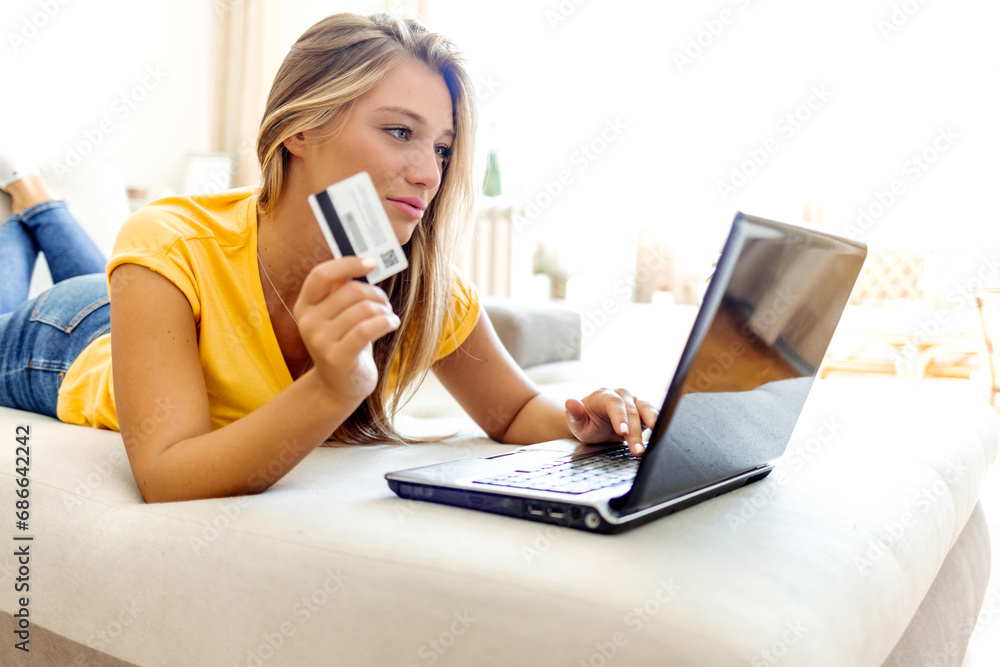 Shot of a cheerful young woman doing online shopping while seating on a couch at home during the day. Cropped shot of a young woman using a credit card to make an online payment at home. Shot of a cheerful young woman doing online shopping while seating on a couch at home during the day. Cropped shot of a young woman using a credit card to make an online payment at home.