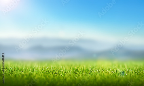  background of a green lawn with a mountain landscape and a blue sky with the rays of the sun