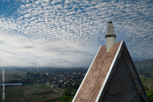 The roof of an old church building with a residential community background and a beautiful sky