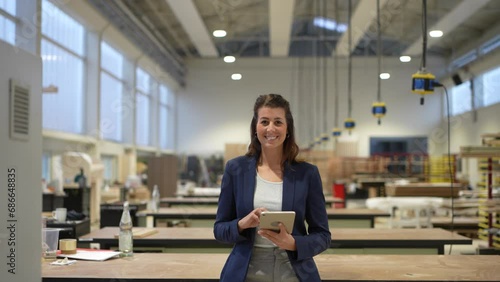 Confident businesswoman holds tablet and smiles into camera photo