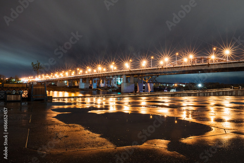 City embankment after rain, night cityscape, light of lanterns on the bridge.