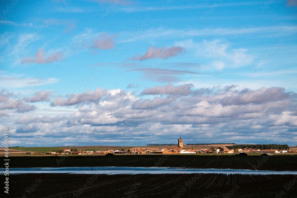 Obraz premium The village of Pajares de Adaja in Castilla y León in Spain, a view of its church, houses and crop fields