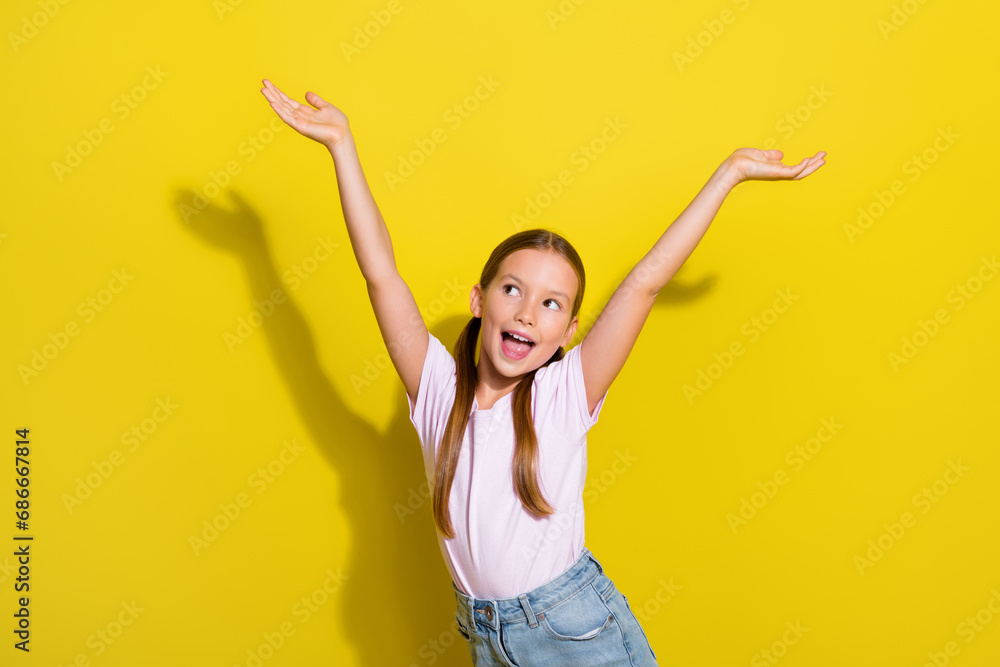 Photo of excited dreamy little child dressed pink t-shirt rising hands arms looking empty space isolated yellow color background Photo of excited dreamy little child dressed pink t-shirt rising hands arms looking empty space isolated yellow color background