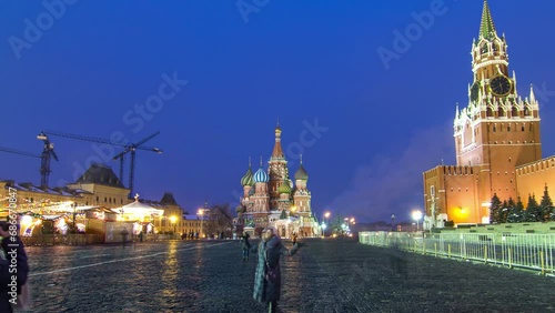 Timelapse of Red Square in Moscow, during the day-to-night transition. The Moscow Kremlin with the iconic Spasskaya Tower and the Cathedral of St. Basil are illuminated, creating a stunning scene.
