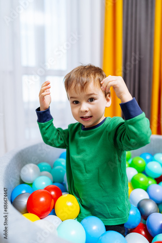 A young boy playing in a ball pit. A Young Boy Having Fun in a Colorful Ball Pit