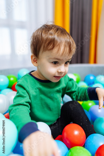 A Playful Adventure in a Colorful Ball Pit. A little boy sitting in a ball pit
