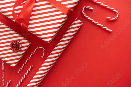 Red and white stripes wrapping paper roll, striped pattern Christmas gift boxes and candy canes decorations. Festive presents composition with copy space. Winter holiday season gift guide concept. photo