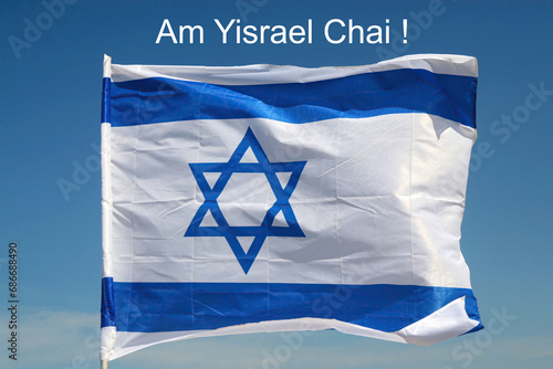 Country Israel flag against blue sky with inscription "Am Yisrael Chai" - The Nation of Israel Lives (עם ישראל חי)