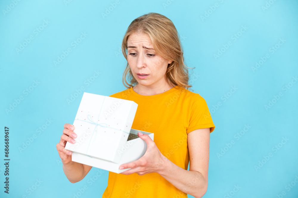 Portrait of sad displeased woman opening gift package Portrait of sad displeased woman opening gift package