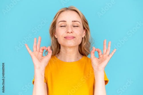 Young satisfied woman with closed eyes raise two hands with OK gesture