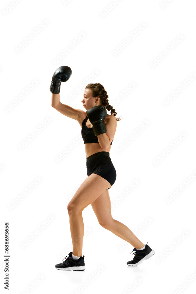 Fototapeta premium Powerful and dynamic, boxer girl, professional sportsman radiates strength and confidence in motion against white studio background.