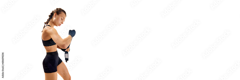 Banner, flyer. Captivating image of skilled female boxer, wrapping her hands in preparation for fight against clean white studio background. Banner, flyer. Captivating image of skilled female boxer, wrapping her hands in preparation for fight against clean white studio background.