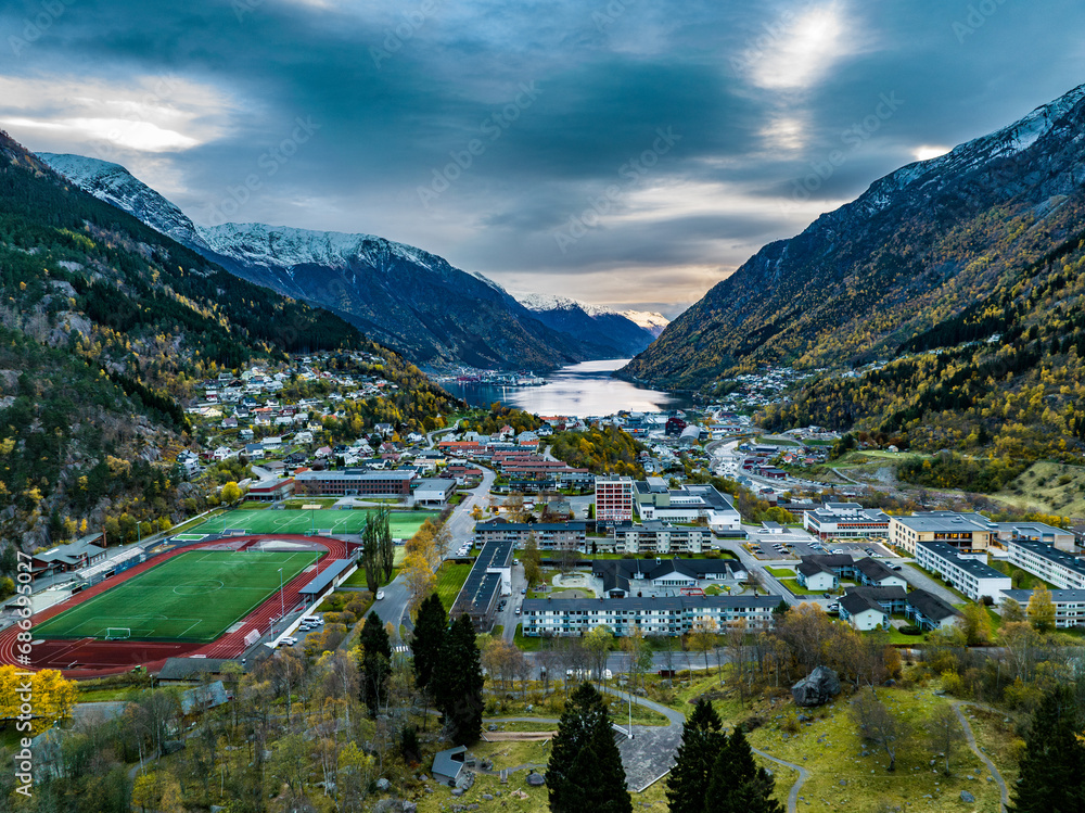 aerial view over town of odda on fjord with mountains covered with snow on background in norway