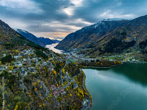 aerial view over town of odda on fjord with mountains covered with snow on background in norway