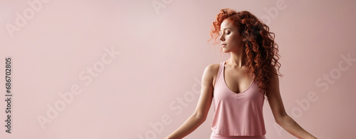 Bellissima donna con capelli ricci color rosso e rosa fa yoga e meditazione al mattino in palestra con vestiti rosa, sfondo colorato