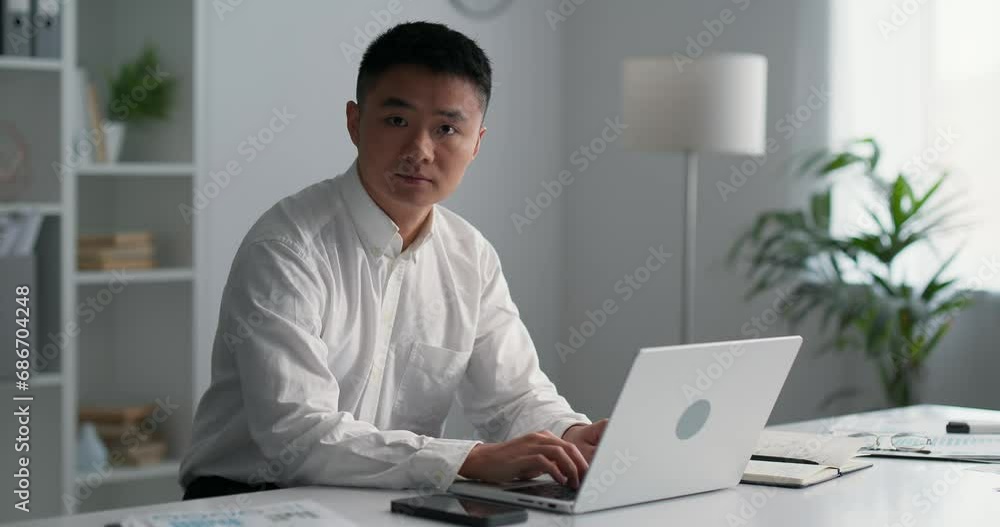 Young asian businessman sitting at his workplace, typing on keyboards at laptop. Young asian businessman sitting at his workplace, typing on keyboards at laptop.