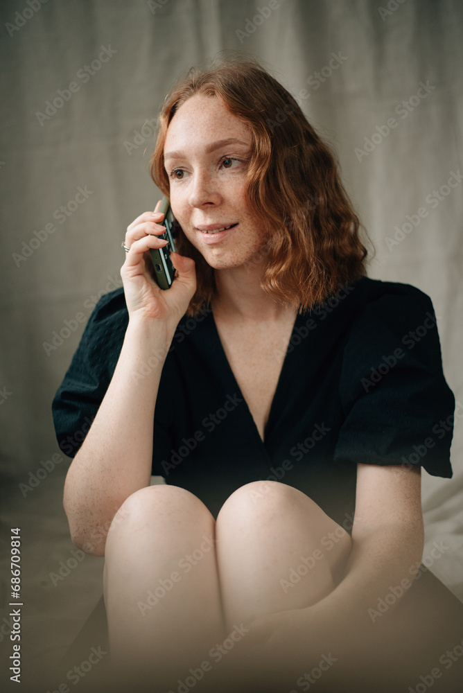 red-haired girl in a black dress with a phone