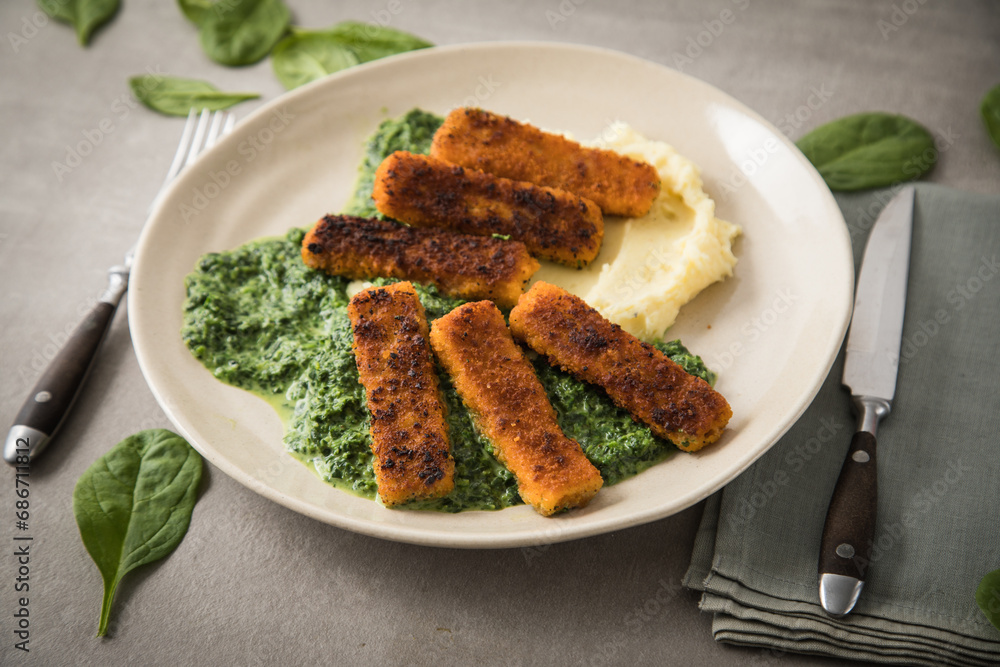 Gebratene Fischstäbchen mit Rahmspinat und Kartoffelpüree auf Teller ...