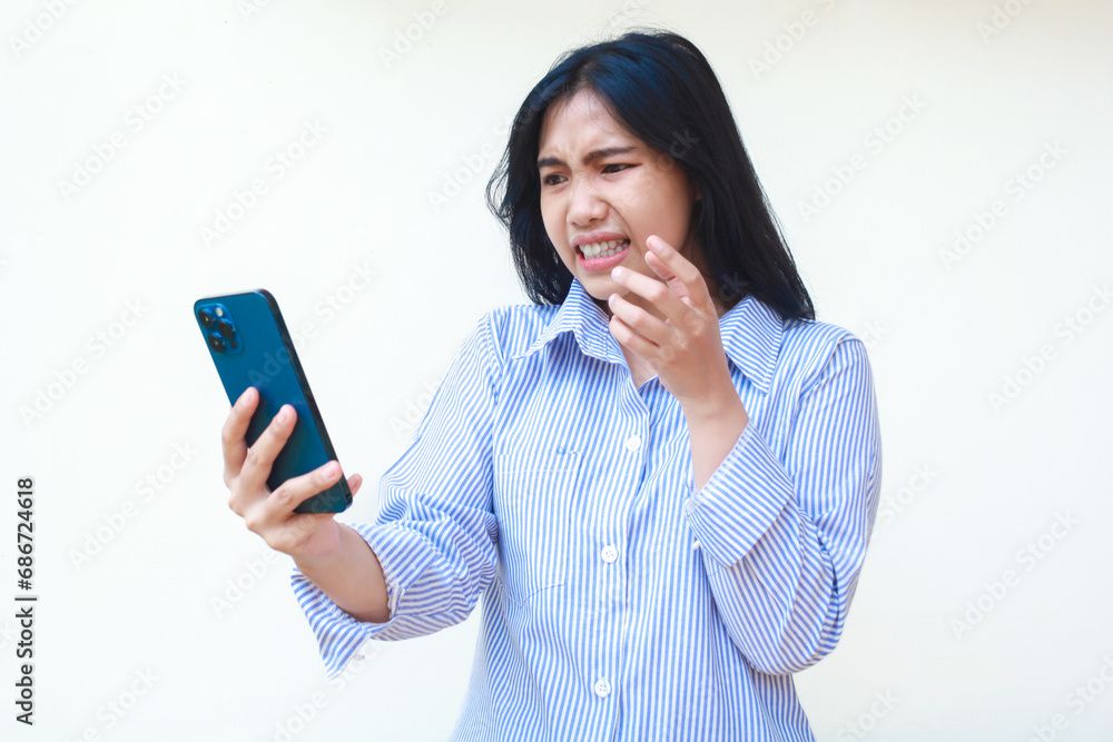 angry asian woman wearing blue stripes shirt holding mobile phone raising palms looks annoyed standing over isolated white background angry asian woman wearing blue stripes shirt holding mobile phone raising palms looks annoyed standing over isolated white background