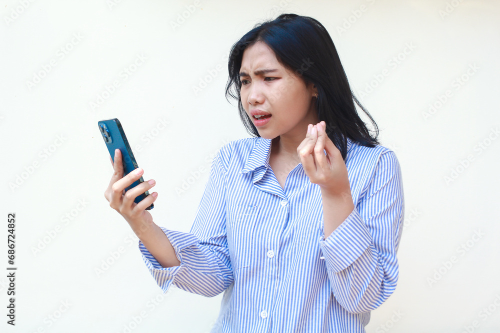 angry asian woman wearing blue stripes shirt holding mobile phone raising palms looks annoyed standing over isolated white background angry asian woman wearing blue stripes shirt holding mobile phone raising palms looks annoyed standing over isolated white background
